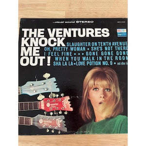 May include: Vintage vinyl record album cover for "The Ventures - Knock Me Out!" featuring a woman with blonde hair and three guitars. The album cover is black with white and blue text, and the Dolton Records logo.