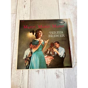 Puede incluir: Portada de álbum de vinilo vintage para "Music, Music, Music" de Teresa Brewer. La portada presenta una imagen en color de Brewer con un vestido verde azulado, cantando, con una banda detrás de ella. El álbum es del sello Coral.