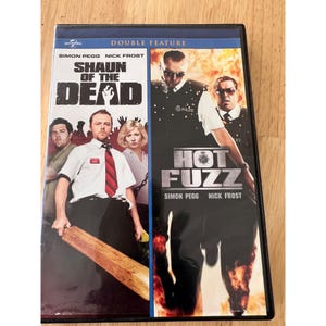 May include: A double feature DVD case featuring the films Shaun of the Dead and Hot Fuzz. The cover displays actors Simon Pegg and Nick Frost in character, with the titles printed in bold white and silver lettering against a background of fire.