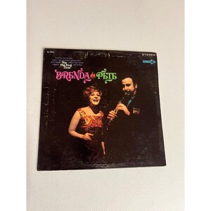 May include: Vintage vinyl record album cover featuring Brenda & Pete. The cover has a dark background with the title "For The First Time" and the names "Brenda & Pete" in pink and green. A woman in a patterned dress and a man playing a clarinet are pictured.