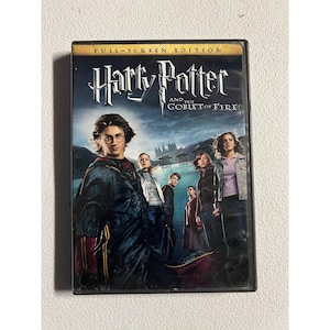 Puede incluir: Caja de DVD de "Harry Potter y el cáliz de fuego". La portada presenta el título de la película en una fuente estilizada. Varios personajes se muestran frente a un fondo oscuro y nublado.