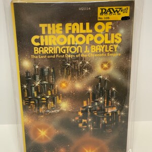 May include: A yellow and black paperback book with the title "The Fall of Chronopolis" by Barrington J. Bayley. The book cover features a futuristic city skyline with stars in the background. The book is a DAW Books publication, number 105.