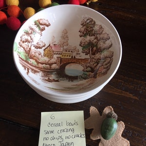 Puede incluir: Seis cuencos de cereales vintage con un dise&ntilde;o de paisaje marr&oacute;n y verde. Los cuencos est&aacute;n apilados y tienen una nota escrita a mano que dice "6 cereal bowls same crazing no chips, no cracks Nasco Japan".