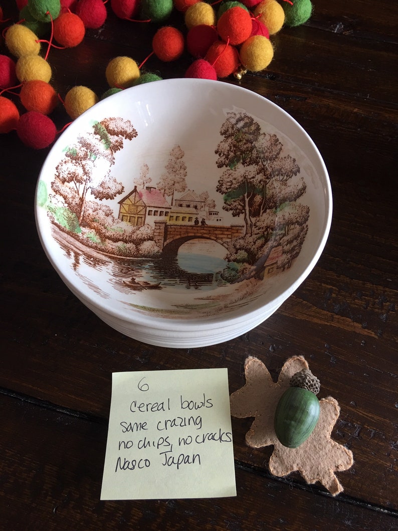 Puede incluir: Seis cuencos de cereales vintage con un dise&ntilde;o de paisaje marr&oacute;n y verde. Los cuencos est&aacute;n apilados y tienen una nota escrita a mano que dice "6 cereal bowls same crazing no chips, no cracks Nasco Japan".