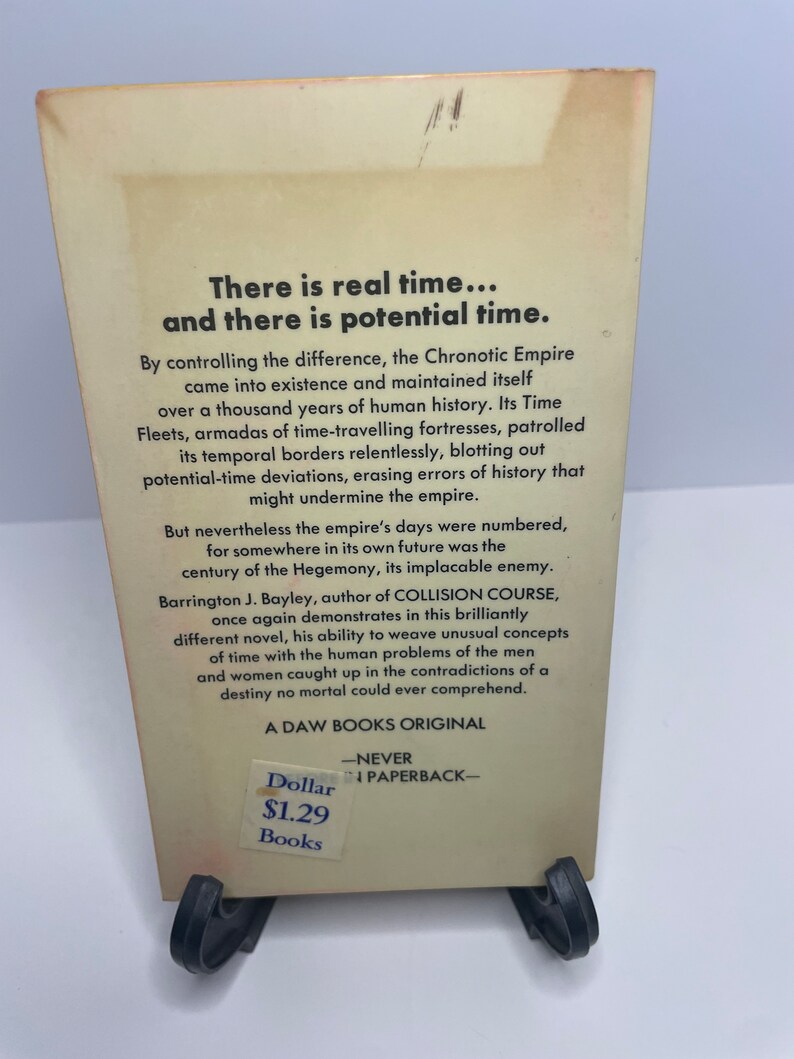 May include: A vintage paperback book cover with a white background and black text. The title is "There is real time... and there is potential time." The book is a science fiction novel by Barrington J. Bayley, author of "Collision Course". The book cover also includes the price of $1.29.