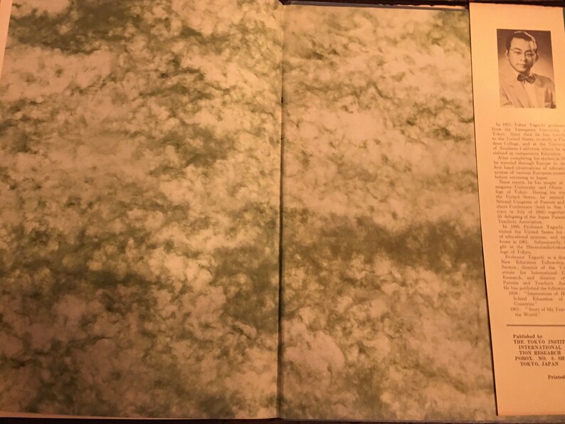 May include: An open book with a marbled cover. The right page features a black and white photograph of a man in a suit and tie. The text on the page details the man's life and career.