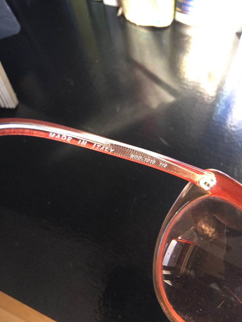 May include: Close-up of the inside of a pair of red sunglasses with the text "MADE IN ITALY MOD. 7010 112" printed on the arm.