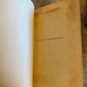 May include: Open book with aged, cream-colored pages. The right page displays the title "THE GATE OF REMEMBRANCE" in a simple, serif font. The book's pages show signs of age, with a warm, sepia tone.