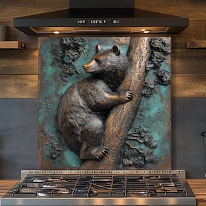 May include: A bronze-colored bear climbing a tree, mounted on a teal and brown background. The artwork is installed above a stainless steel gas range in a kitchen setting. Wooden shelves and a black range hood are also visible.