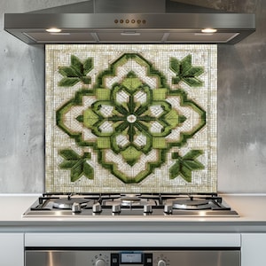 Könnte beinhalten: Eine dekorative Mosaik-Rückwand mit einem grün-weißen Blumendesign. Die Rückwand ist über einem Gasherd und unter einer Edelstahl-Dunstabzugshaube installiert. Das Mosaikmuster zeigt eine zentrale Blume und Blätter.