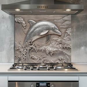 May include: A silver-colored backsplash featuring a 3D relief of a dolphin leaping through ocean waves. The artwork includes detailed depictions of water, clouds, and rocky formations, creating a dynamic and aquatic scene.