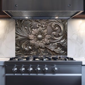 May include: A decorative kitchen backsplash with a detailed, embossed floral design. The silver-toned panel features a large flower and swirling leaf patterns, installed above a stainless steel stove.