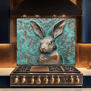 Puede incluir: Una escultura de conejo en tonos cobrizos con largas orejas y pelaje detallado está montada sobre un fondo turquesa texturizado. La obra de arte está instalada sobre una estufa de gas de acero inoxidable con perillas doradas, creando un diseño de cocina único.