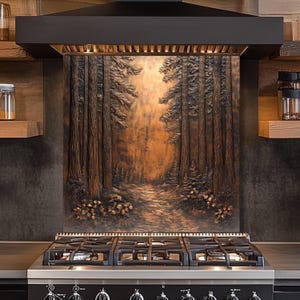May include: A copper-colored kitchen backsplash with a detailed forest scene. The artwork features tall trees, a path, and foliage, creating a three-dimensional effect. The backsplash is installed above a black gas range.