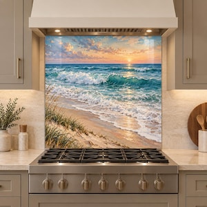 May include: A rectangular kitchen backsplash panel featuring a printed landscape of a beach at sunset. The image displays turquoise ocean waves crashing onto a sandy shore with tall beach grass in the foreground under a soft orange sky.