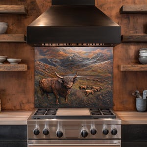 May include: A kitchen backsplash features a relief sculpture of a Highland cow in a field with mountains in the background. The artwork is above a stainless steel gas range and below a black range hood. Wooden shelves and copper-toned walls complete the kitchen.