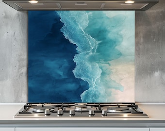 May include: A glass kitchen backsplash featuring an abstract ocean wave design in shades of blue and white. The artwork is mounted behind a gas stovetop and beneath a stainless steel range hood.