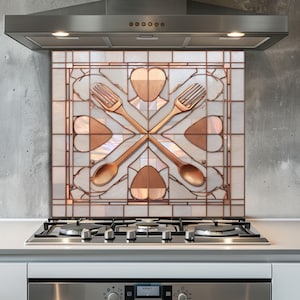 May include: A decorative kitchen backsplash featuring a copper-colored design of crossed forks and spoons, with heart-shaped accents. The backsplash is set against a white and iridescent background, above a stainless steel gas stovetop.