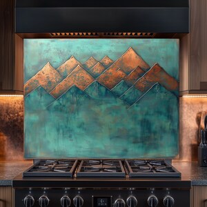 Op de afbeelding: Een koper- en zeegroen bergketenontwerp backsplash boven een zwart gasfornuis. Het kunstwerk toont een gelaagde bergsc&egrave;ne met koperen toppen en zeegroene valleien, wat een rustieke toets aan de keuken toevoegt.