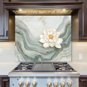 May include: A decorative kitchen backsplash featuring a white lotus flower with a golden center, set against a backdrop of swirling teal and gold marble-like patterns. The backsplash is installed above a stainless steel gas range.
