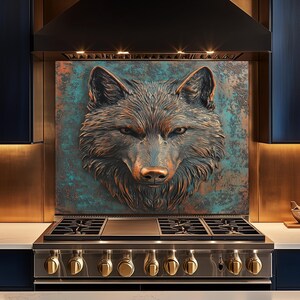 Puede incluir: Escultura de cabeza de lobo en tonos cobrizos montada sobre una cocina de gas de acero inoxidable. La cara del lobo tiene detalles intrincados y está sobre un fondo turquesa y bronce. La cocina presenta gabinetes azul oscuro y detalles dorados.