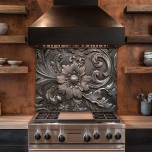 May include: A stainless steel gas range with a decorative backsplash featuring a large floral design. The backsplash is made of a dark metal with a raised, detailed pattern. The kitchen also includes wooden shelves and a range hood.