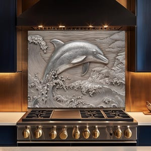 May include: A stainless steel kitchen backsplash featuring a detailed relief of a dolphin leaping from ocean waves. The dolphin and waves are rendered in a metallic silver finish, creating a 3D effect. The backsplash is installed above a stainless steel gas range.