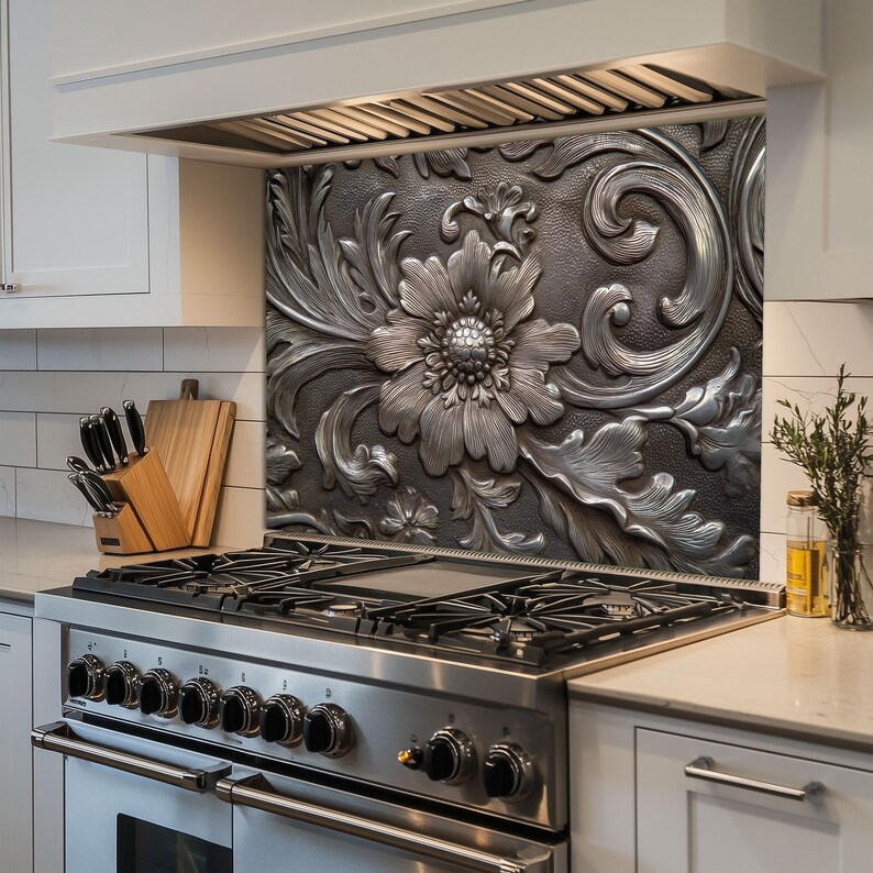 May include: A decorative kitchen backsplash with a large, embossed floral design. The backsplash is made of a dark gray metal with a raised, silver-colored floral pattern. The design includes a large flower and swirling leaves.