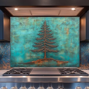 Puede incluir: Un protector contra salpicaduras de metal en tonos cobre con un diseño detallado de árbol sobre un fondo turquesa y verde azulado. El árbol es una silueta detallada, que añade un elemento rústico a la decoración de la cocina. El protector está instalado sobre una estufa de acero inoxidable.