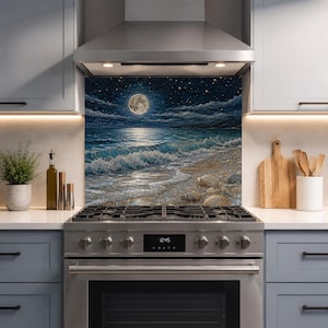 Puede incluir: Un panel protector de cocina que muestra un paisaje marino nocturno con luna llena, cielo estrellado y olas rompiendo en una orilla arenosa con conchas marinas. La escena presenta tonos azul oscuro, blanco y arena, situada tras una estufa de acero.