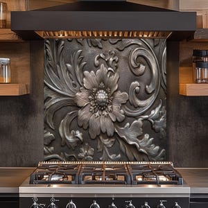 May include: A decorative kitchen backsplash with a raised floral design in shades of gray and silver. The intricate pattern features a large flower and swirling leaves, adding a touch of elegance to the cooking area. The backsplash is installed above a black gas range.