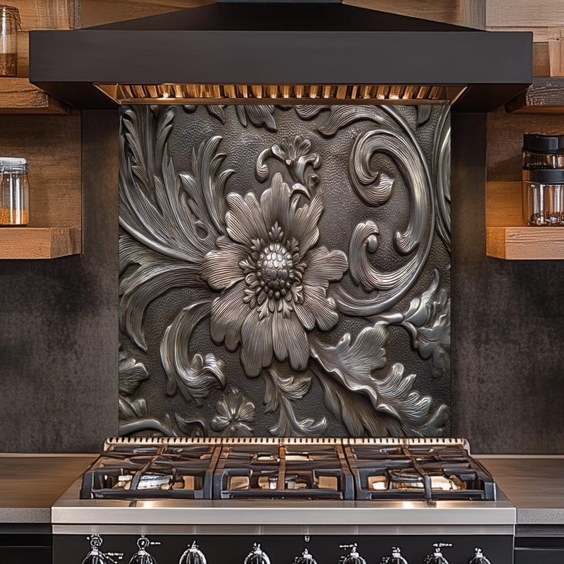 May include: A decorative kitchen backsplash with a raised floral design in shades of gray and silver. The intricate pattern features a large flower and swirling leaves, adding a touch of elegance to the cooking area. The backsplash is installed above a black gas range.