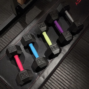 May include: Six black 25-pound dumbbells with different colored handles. The handles are pink, red, blue, yellow, purple, and gray.