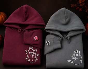Könnte beinhalten: Ein kastanienbrauner Kapuzenpullover mit einem weißen Geister-Linienbild mit Heiligenschein und ein grauer Kapuzenpullover mit einem weißen Geister-Linienbild mit Hörnern. Beide haben ein kleines gesticktes Herz am Ärmelbündchen.