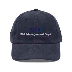 May include: Navy blue corduroy baseball cap with the text "svb" in blue and "Risk Management Dept." in white. The cap has a curved brim and a fabric strap closure.