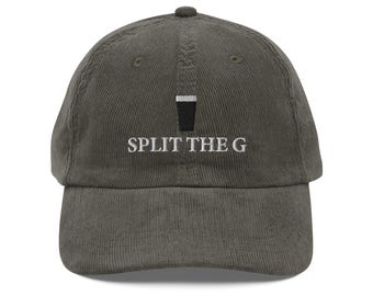 Puede incluir: Gorra de béisbol de pana verde oliva. La gorra presenta el texto bordado "SPLIT THE G" en blanco, con un gráfico en blanco y negro de un vaso de pinta encima. Tiene una visera curva y un botón en la parte superior.