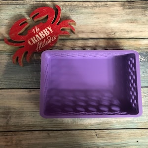 May include: A purple rectangular basket with a textured design. A red wooden crab with the text "No Crabby Attitudes" is next to the basket. The basket is empty and sits on a wooden surface.