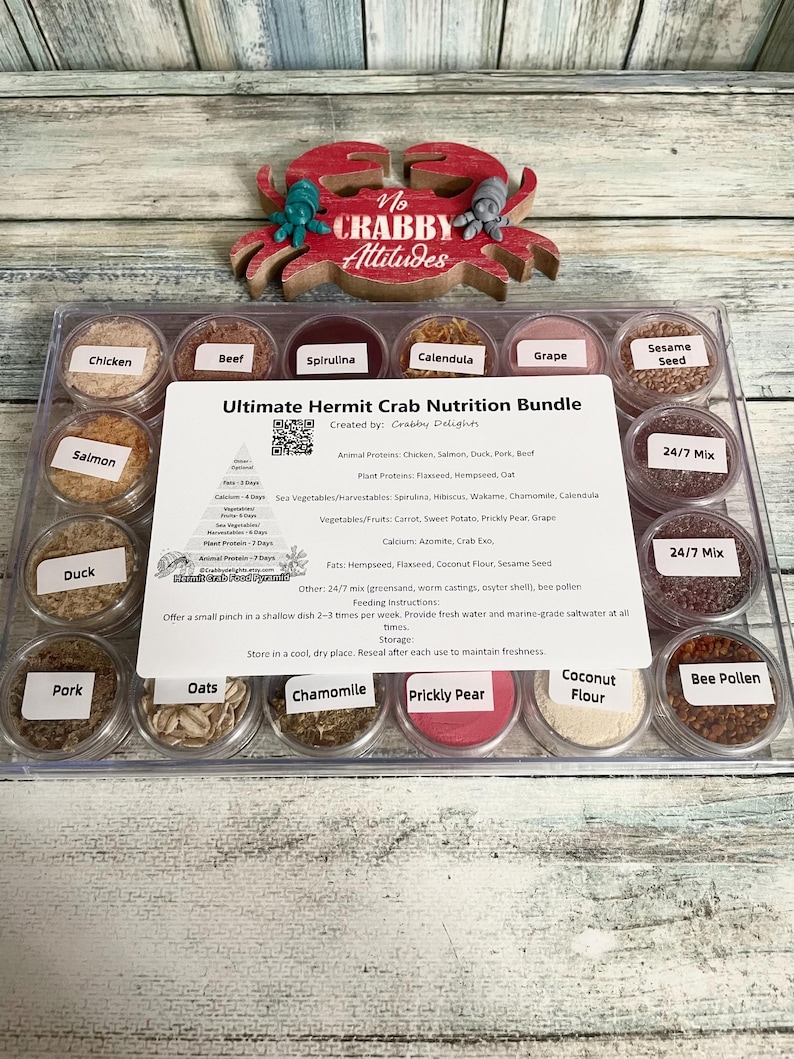 May include: A clear plastic container filled with small, labeled jars of hermit crab food. The labels include ingredients like chicken, spirulina, and chamomile. A red crab-shaped decoration sits above the container, with the words "No Crabby Attitudes".