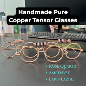 Peut inclure: Lunettes tensor en cuivre pur faites à la main avec des montures en fil torsadé et des verres circulaires. Le design comprend trois accents de pierres précieuses distincts : quartz rose, améthyste et lapis-lazuli, chacun serti dans une petite section de fil de cuivre enroulé.