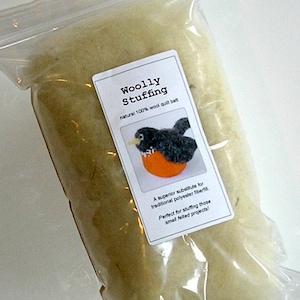May include: A clear plastic bag filled with natural 100% wool quilt batting. The bag has a label that reads "Woolly Stuffing" and includes a small illustration of a robin. The label also states "A superior substitute for traditional polyester fiberfill. Perfect for stuffing those small felted projects!"