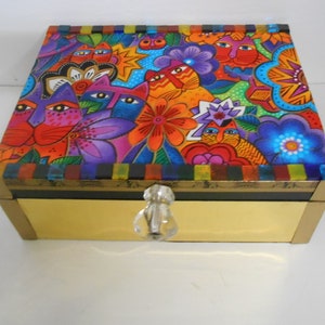 May include: A colorful wooden box with a whimsical design featuring cats and flowers. The box has a gold lid and a crystal knob.