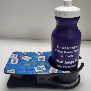 May include: A black and blue Mah Jongg themed cup holder with a purple water bottle. The water bottle has the text "I'm addicted to Craks, Bams, Dots & Jokers Mah Jongg is my Passion!" printed on it.