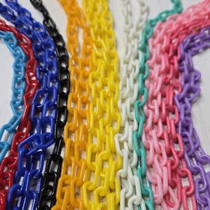 May include: A collection of colorful plastic chains in various hues, including red, blue, black, yellow, white, green, pink, and purple. The chains are linked together, creating a vibrant and eye-catching display.