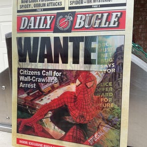May include: A Daily Bugle newspaper poster with a vintage design. The headline reads "WANTED" with a picture of Spider-Man. Text includes "Citizens Call for Wall-Crawler's Arrest" and "Police Offer Reward for Capture."