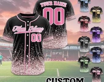 May include: Black baseball jersey with pink accents and a glitter effect. The front features "Team Name" and the number "00". The back displays "YOUR NAME" and "00". Additional jerseys in various colors are shown. Text at the bottom reads "CUSTOM ANY REQUEST".