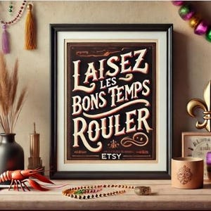 以下が含まれることがあります： ヴィンテージスタイルのフォントで「Laissez les bons temps rouler」というテキストが書かれた額装されたプリント。プリントは暗い背景に白い文字で、金色の縁取りが施されています。プリントは、金色のフルール・ド・リス、木製の箱、ビーズのガーランドなど、他の装飾品と一緒に木製のテーブルの上に置かれています。
