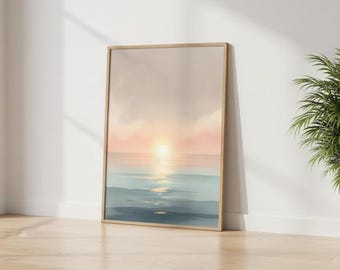 May include: A framed art print depicting a serene sunset over the ocean. The artwork features a gradient of colors, with a bright yellow sun reflecting on the water, transitioning to pink and blue hues. The print is displayed on a wooden floor.