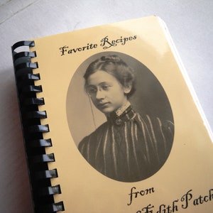 May include: A vintage cookbook with a yellow cover and a black spiral binding. The cover features a black and white photo of a woman wearing glasses and a striped dress. The title of the book is "Favorite Recipes from Edith Patch".