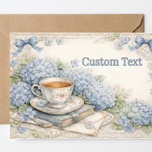 May include: A watercolor-style greeting card with a teacup, saucer, and books, surrounded by blue hydrangeas and bows. The card has the text "Custom Text" and is set against a kraft paper envelope.