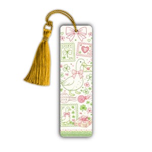 Peut inclure: Marque-page blanc avec un pompon doré. Le marque-page présente un canard avec un nœud papillon, des timbres, des trèfles et des nœuds verts et roses. Le texte "LUCKY" et "GOOD LUCK" est également visible.